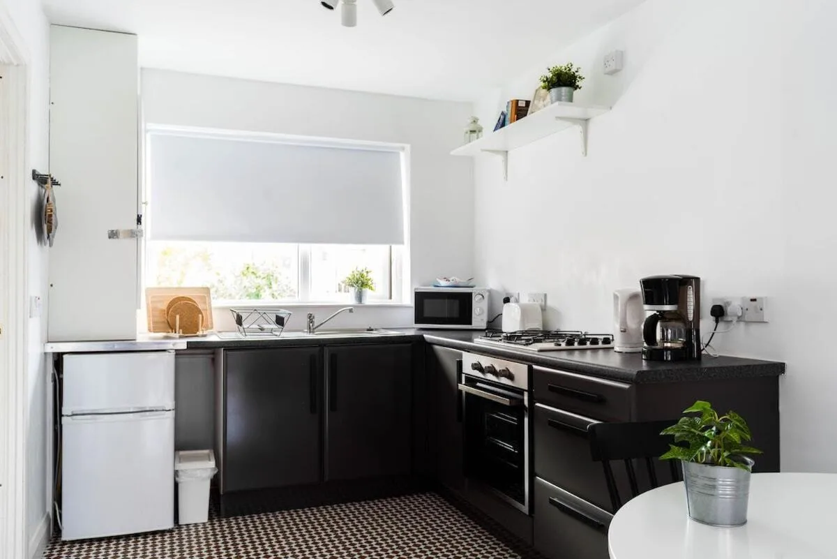 a kitchen with black and white appliances and a window at Amica Guesthouse in Belfast